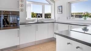 A modern kitchen with white cabinets, a stainless steel oven, and a large window providing a view of the outdoors. - "Rosamunde" - 700m from the sea by Interhome (Sydals)