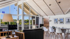 A spacious living area with a large window, a dining area with white chairs, and a black sofa. - "Rosamunde" - 700m from the sea by Interhome (Sydals)