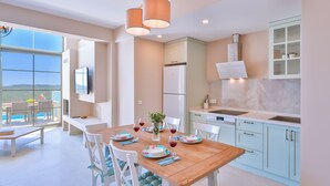 Une cuisine moderne avec une table à manger en bois, des chaises blanches et une vue sur l’extérieur.