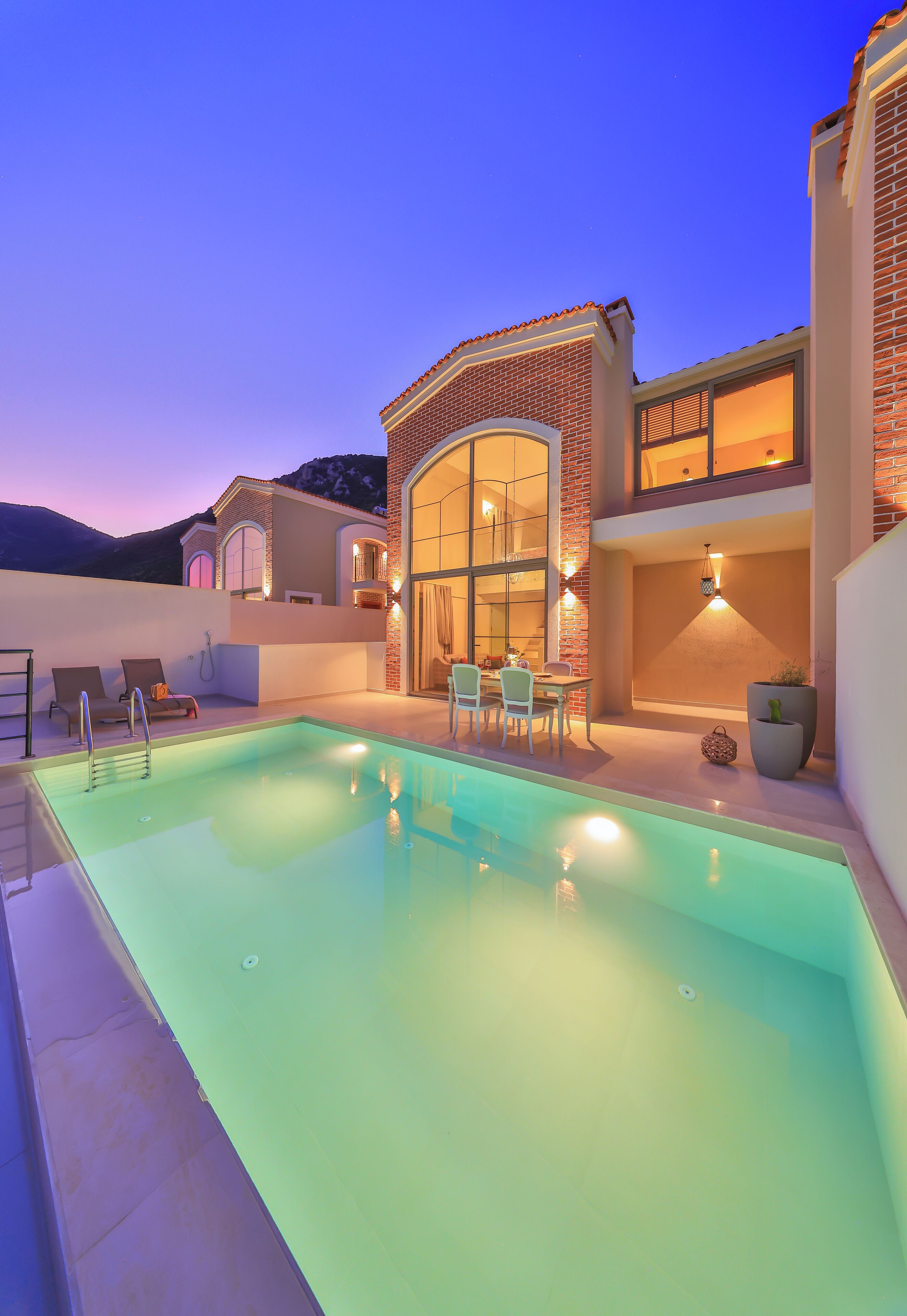 A modern house with a swimming pool, outdoor seating, and a large glass door.