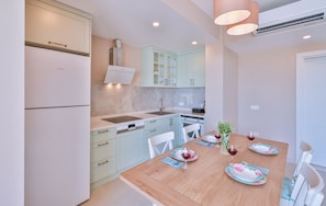 A modern kitchen with light blue cabinets, a wooden dining table set with plates, glasses, and a plant.