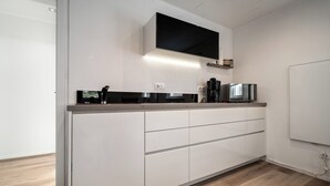 A modern kitchen with white cabinetry, a black countertop, and a built-in microwave. - Modern vacation home Kira with covered terrace and cozy garden in Rech (Rechlin)