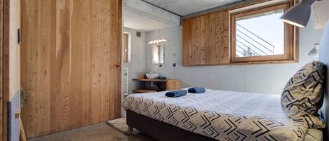 Une chambre à coucher avec un lit, une armoire en bois, une fenêtre et une lampe de chevet.