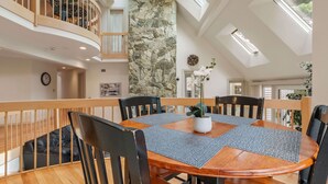 Un espace repas avec une table ronde, des chaises noires et un mur en pierre.