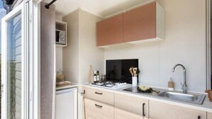 A modern kitchen with a microwave, stove, and sink. - Prestige Mobile Home with Terrace - 4 people, 2 bedrooms (Soustons)