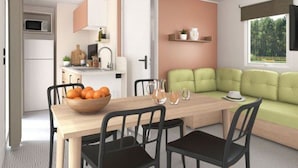 A compact living space with a dining area, kitchenette, and a green sofa. - Prestige Mobile Home with Terrace - 4 people, 2 bedrooms (Soustons)