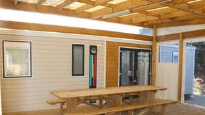 Eine Holzterrasse mit Picknicktisch, Holzbalken und einer Garagentür.