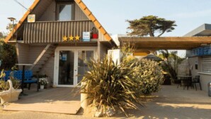 A small, triangular-roofed building with a porch and outdoor seating area. - Mobile home - Terrace for 4 people in Saint-Michel-Chef-Chef (Saint-Michel-Chef-Chef)
