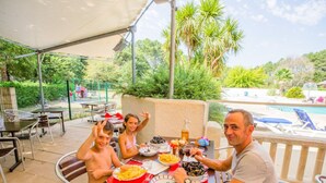 Een terras met een tafel, stoelen en een zwembad op de achtergrond.