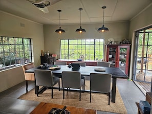 Uma sala de jantar com uma mesa grande, cadeiras e luminárias pendentes.