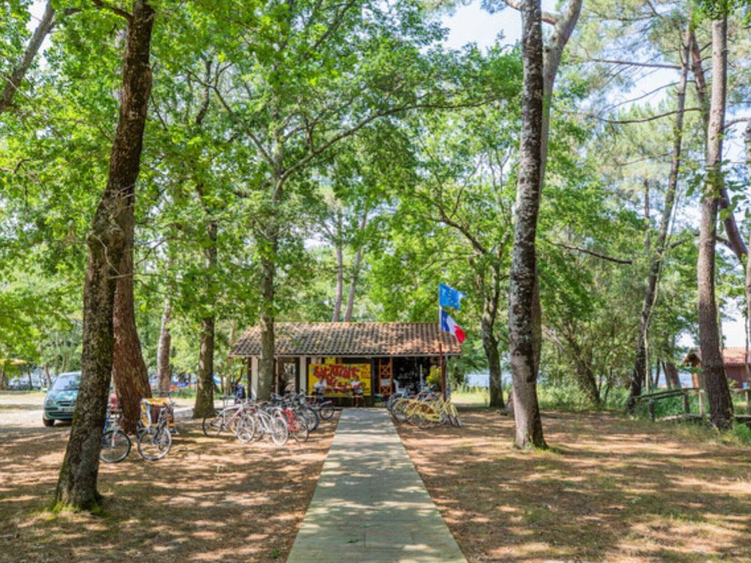 Un piccolo edificio con tetto in tegole, circondato da alberi e un vialetto.
