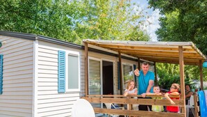 A mobile home with a wooden deck and a satellite dish.