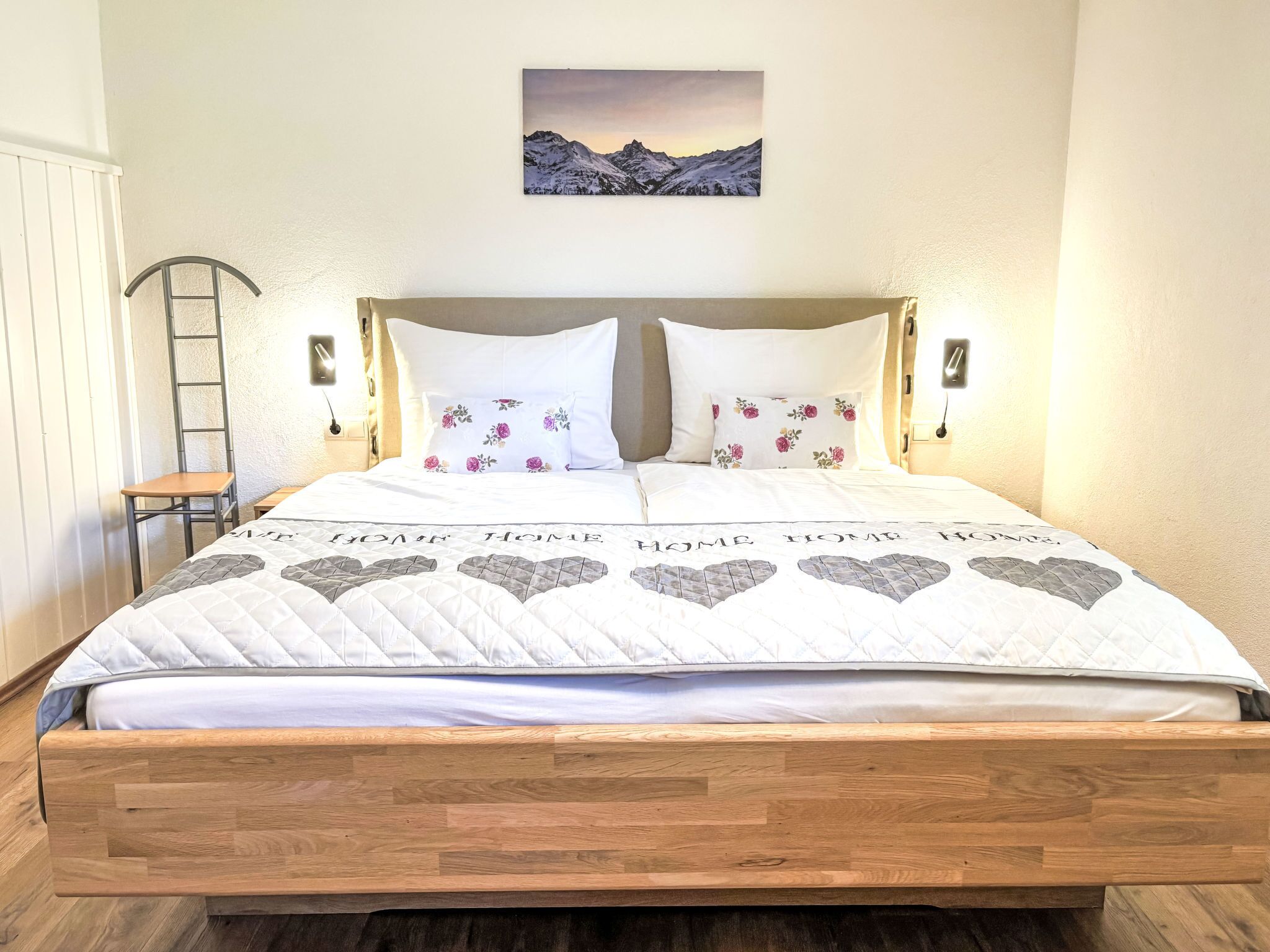 A bed with a quilted headboard, a wooden bedside table, and a nightstand with a lamp.