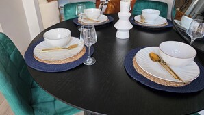 A dining table set with white bowls, gold cutlery, and clear wine glasses, surrounded by green upholstered chairs. - Spacious| Modern House |Close to Sites, beach,|Contractors,  families welcome (Yeovil)