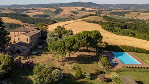 Une villa avec piscine, entourée de douces collines et sous un ciel dégagé.