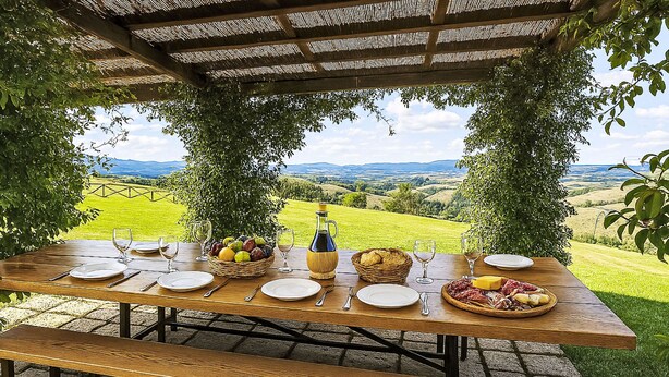 An outdoor dining table with a view of a green landscape and mountains.