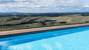 A swimming pool with a view of rolling hills and a cloudy sky.