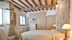 A bedroom with a bed, a dresser, a chair, and a table with a lamp.