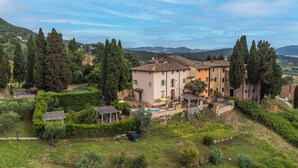 A villa with a swimming pool, surrounded by lush greenery and hills.