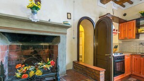 A kitchen with a brick fireplace, wooden cabinets, and a tiled backsplash.