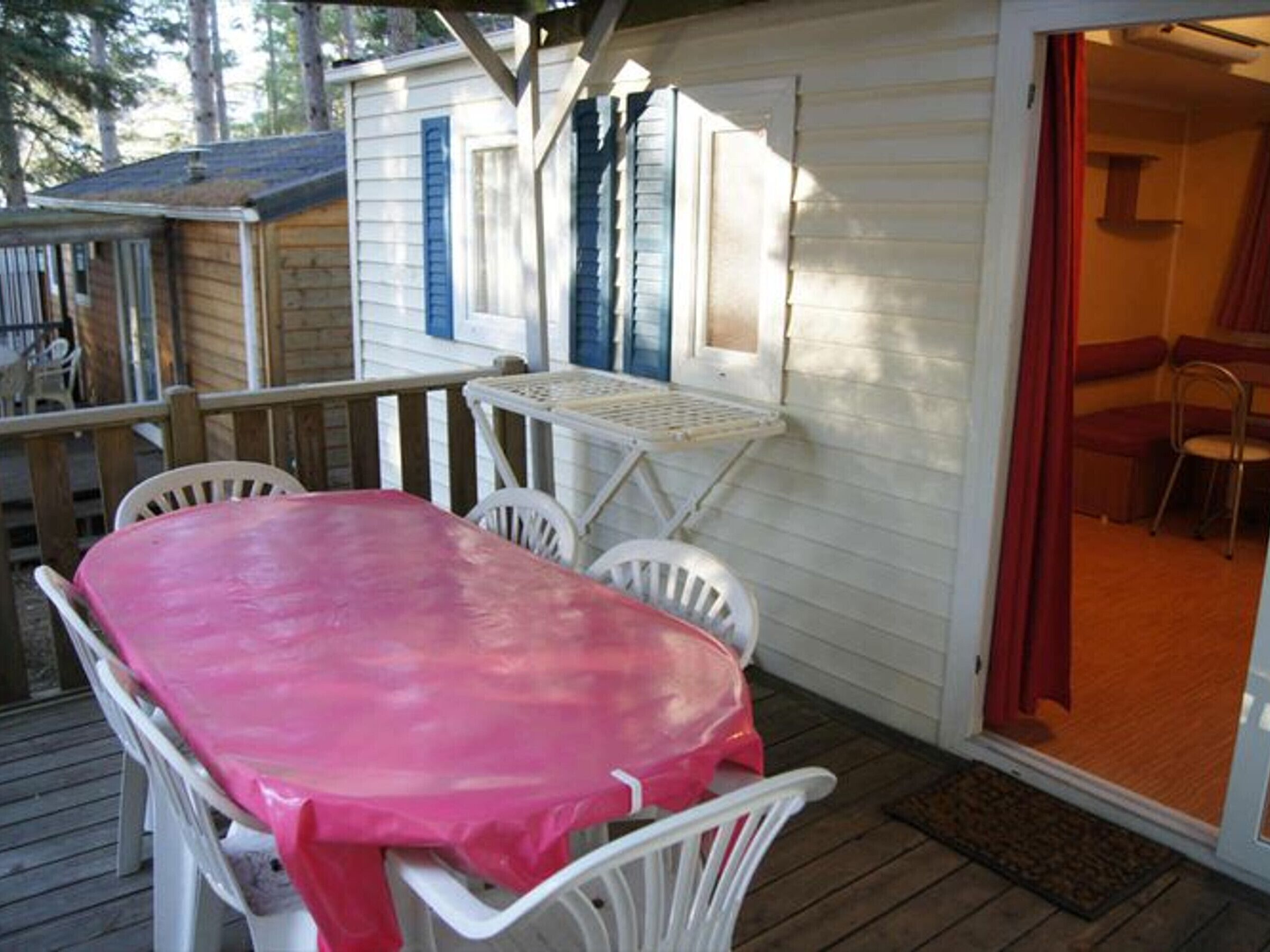 A covered outdoor area with a table and chairs, a small table with a chair, and a door leading to an interior room.