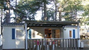 A small cabin with a porch, wooden deck, and a covered area with chairs. - Cozy mobile home with terrace in Sournia (Sournia)