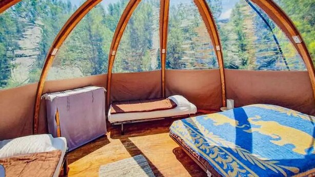 A cozy, circular room with a bed, a small table, and a cushioned bench. - Chalet for 6 with Terrace (Fenouillet)
