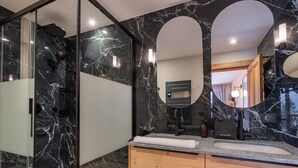 A modern bathroom with a glass-enclosed shower, a vanity with a marble countertop, and a large mirror.