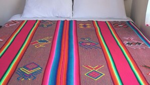 Un lit avec une couverture colorée et deux oreillers blancs.