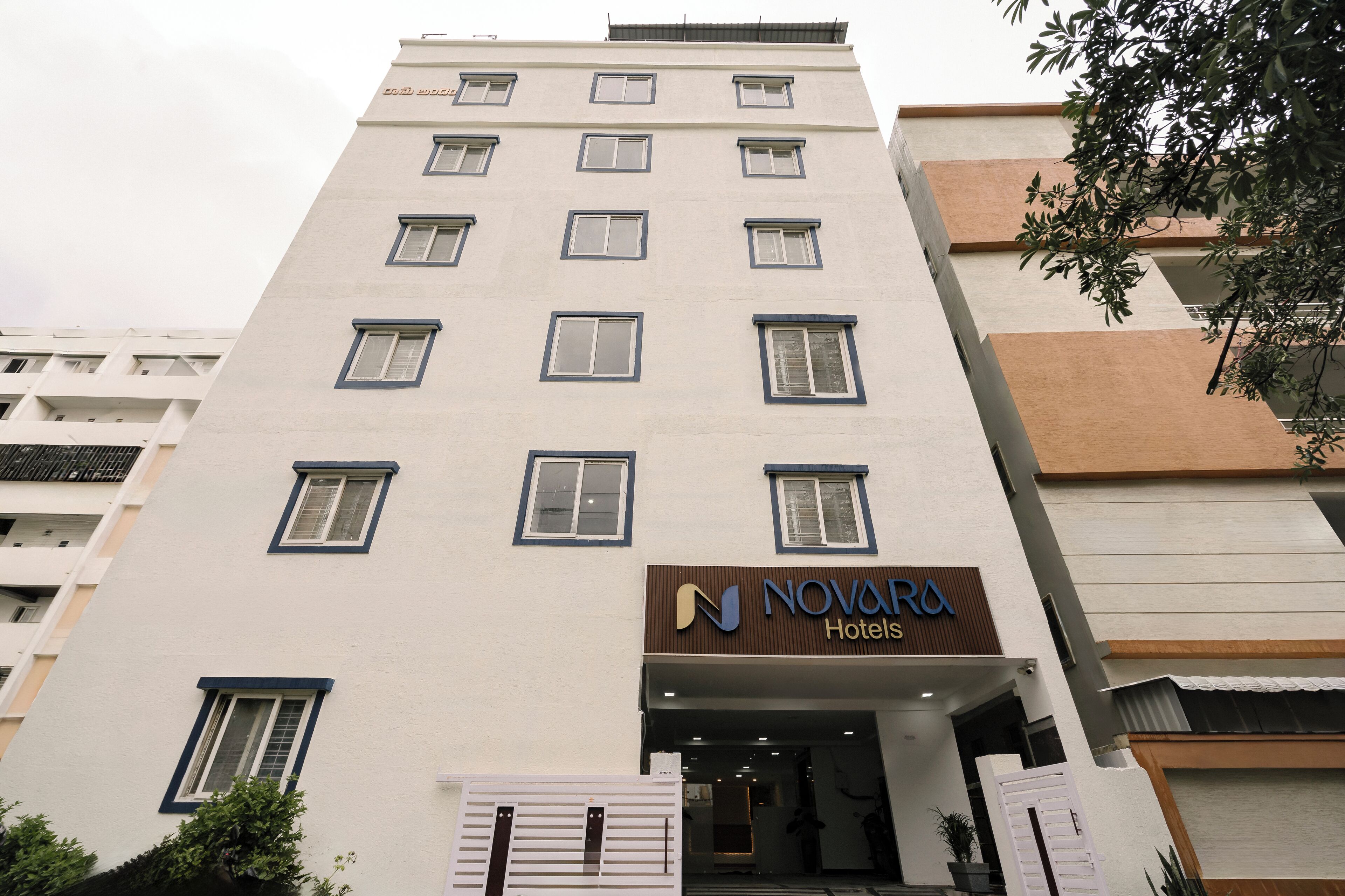 Un hotel de varios pisos con fachada moderna, que presenta un llamativo letrero de 'NOVARA Hotels' en la entrada.