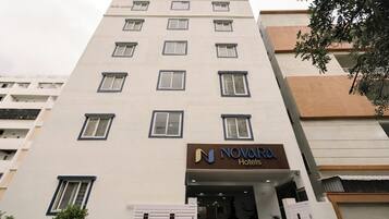 Un hotel de varios pisos con fachada moderna, que presenta un llamativo letrero de 'NOVARA Hotels' en la entrada.