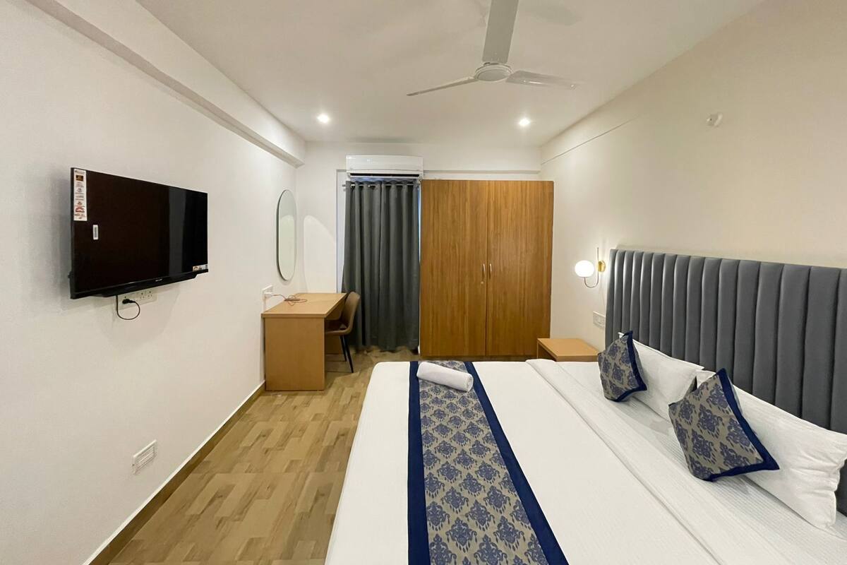 Una habitación de hotel con cama, escritorio, armario, televisor y ventilador de techo.