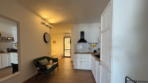 A spacious living area with a sofa, a dining table, and a kitchen area with white cabinets and a black range hood.