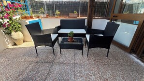 A patio with a table and four chairs, surrounded by potted plants and a blue fence.