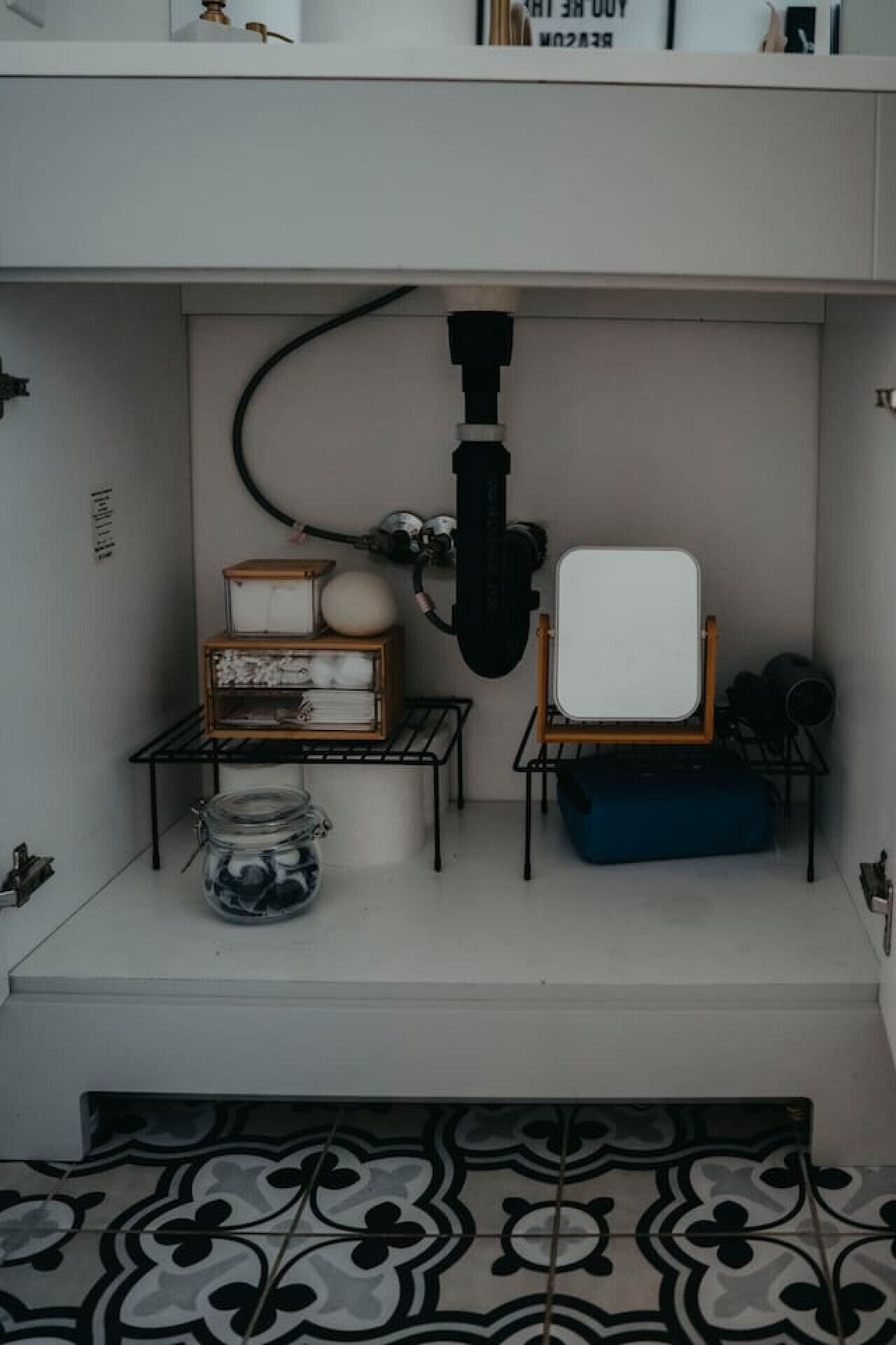 Een kleine, afgesloten ruimte met een wit schap, een witte stoel, een blauw kussen, een houten doos en een glazen pot.