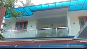 A two-story house with a balcony, a tiled roof, and a porch. - Marari beach daze homestay (Alappuzha)