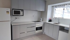 Een kleine keuken met een ingebouwde magnetron, oven en spoelbak.