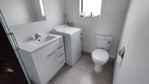 Een badkamer met een wit wastafel, een spiegel, een toilet en een raam.