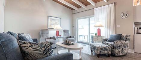 Un salón moderno con techo alto, una mesa de centro redonda y vistas al exterior.