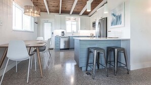 A modern kitchen with a central island, bar stools, and a dining area with chairs. - Casa Mar - 58 Premium Plus (Sarasota)