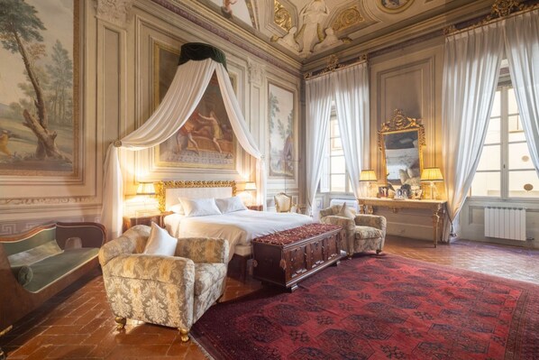 A luxurious bedroom with a four-poster bed, ornate furniture, and a large red carpet.
