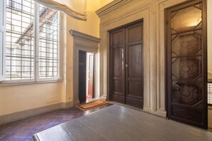 Ein Zimmer mit einem großen Fenster, einer dunklen Holztür und einer Tür mit Musterglas.