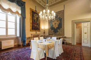 Ein formeller Speisesaal mit einer Chandelier, aufwendigen Wandmalereien und einem großen Teppich.