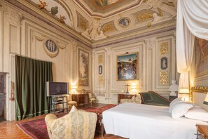 A luxurious hotel room with a large bed, a television, and a green curtain.