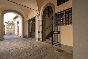 A stone-paved courtyard with arched doorways and a staircase with metal railings.