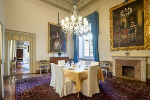 A formal dining room with a chandelier, a large painting, and a fireplace. - Ricasoli Luxury Palace  (Firenze)