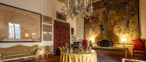 A luxurious room with ornate decor, a large tapestry, and a chandelier.