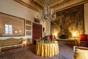 A luxurious room with ornate decor, a large tapestry, and a chandelier.