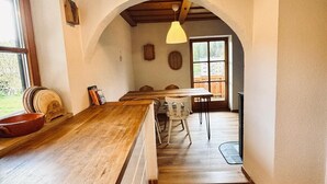 A kitchen with wooden countertops, a dining area with a table and chairs, and a view through an archway to another room.