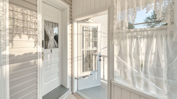 A white wooden porch with a door and a window with lace curtains. - Charming 1-bedroom apartment in welcoming Carbondale with AC (Carbondale)